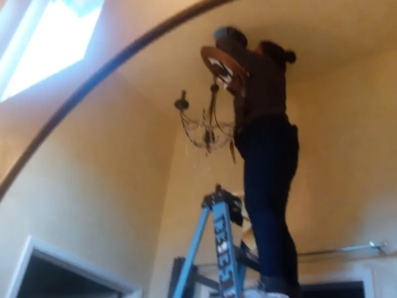 Electrician installing a chandelier in a Laurel residence